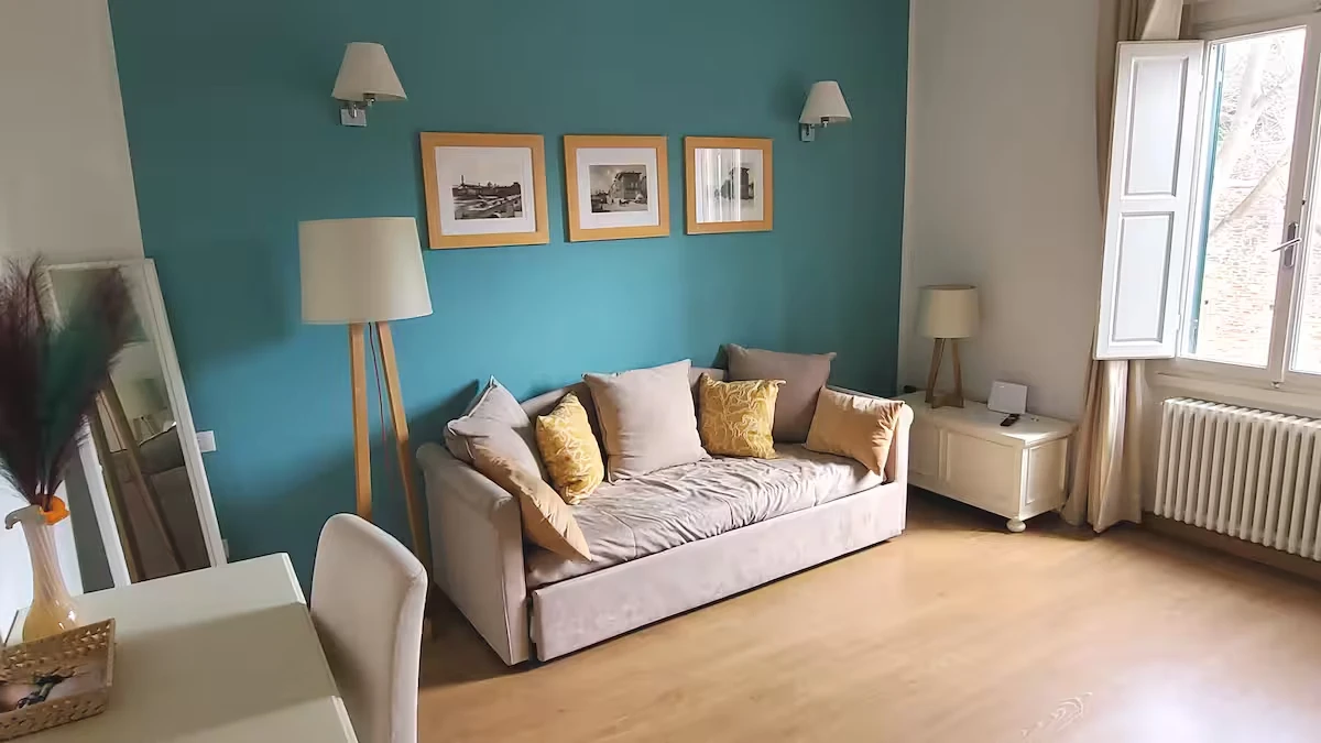 Soggiorno luminoso con parete turchese e arredi moderni, gestito da Phoenix Rental Solutions, property manager per affitti brevi.